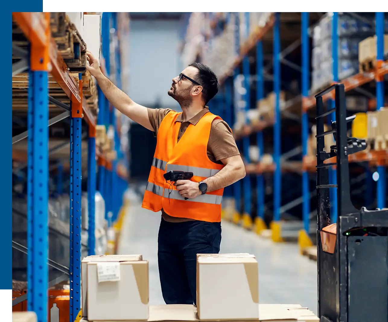 A man in an orange vest is working on some boxes.