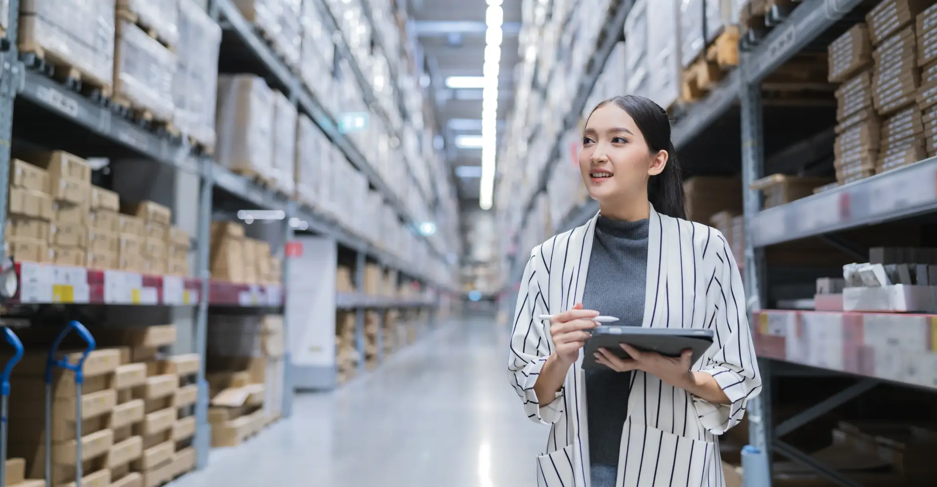 A woman holding a tablet in a warehouse.